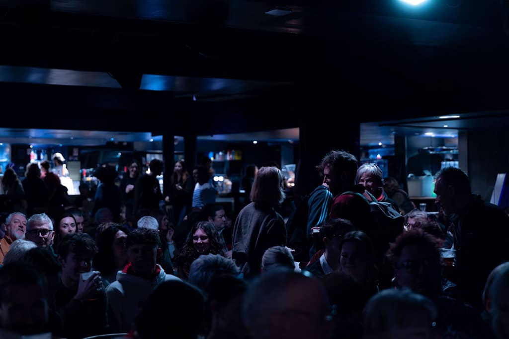 A dark image with a silhouette of an audience is highlighted in a blue light.
